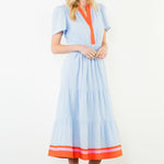 Woman wearing a light blue dress with orange accents against a white background