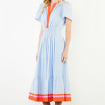 Woman wearing a light blue dress with orange accents on a white background