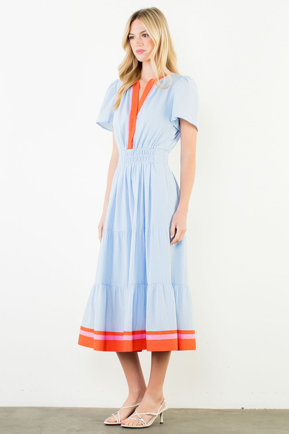 Woman wearing a light blue dress with orange accents on a white background