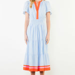 Woman wearing a light blue dress with orange accents on a white background