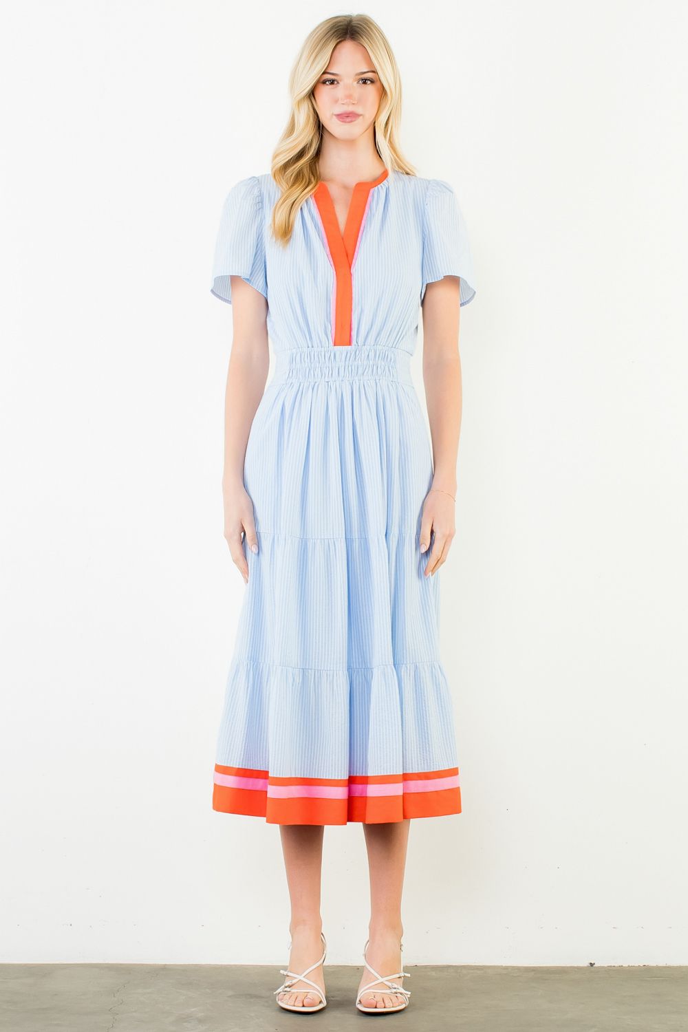 Woman wearing a light blue dress with orange accents on a white background