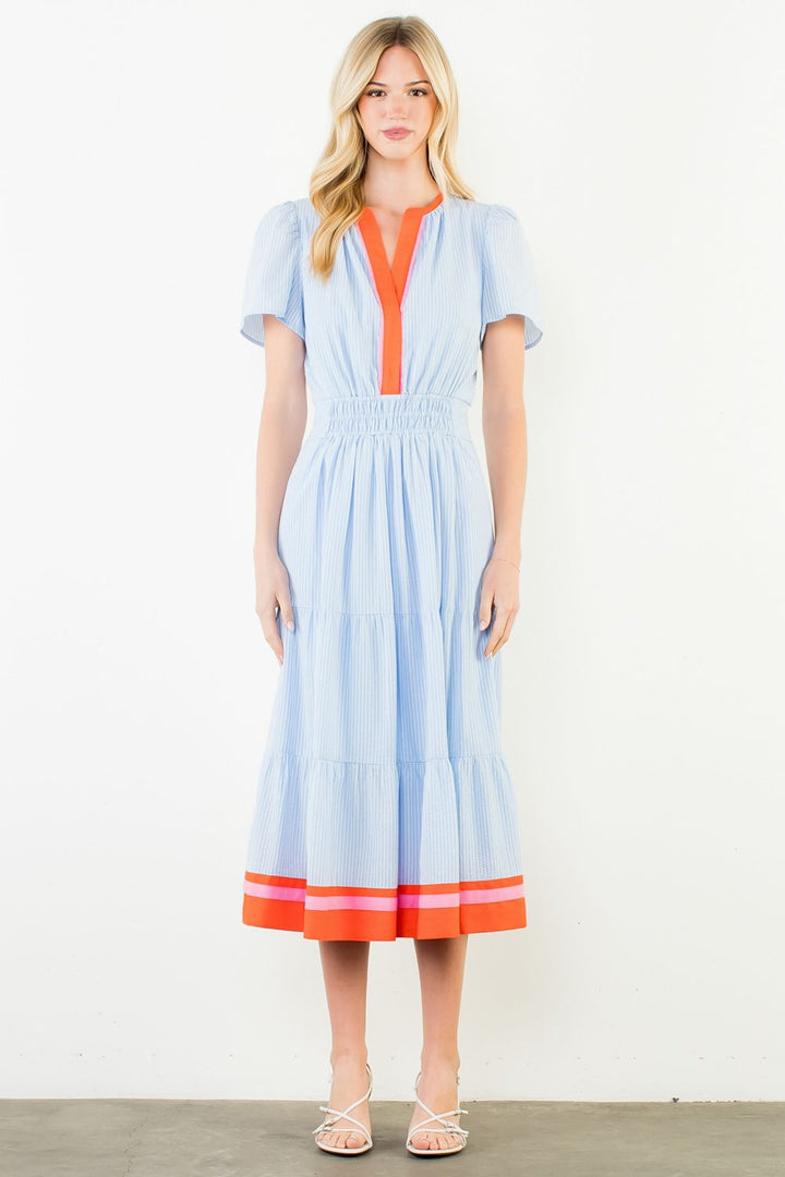Woman wearing a light blue dress with orange accents on a white background