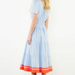 Woman wearing a light blue dress with red trim on a white background