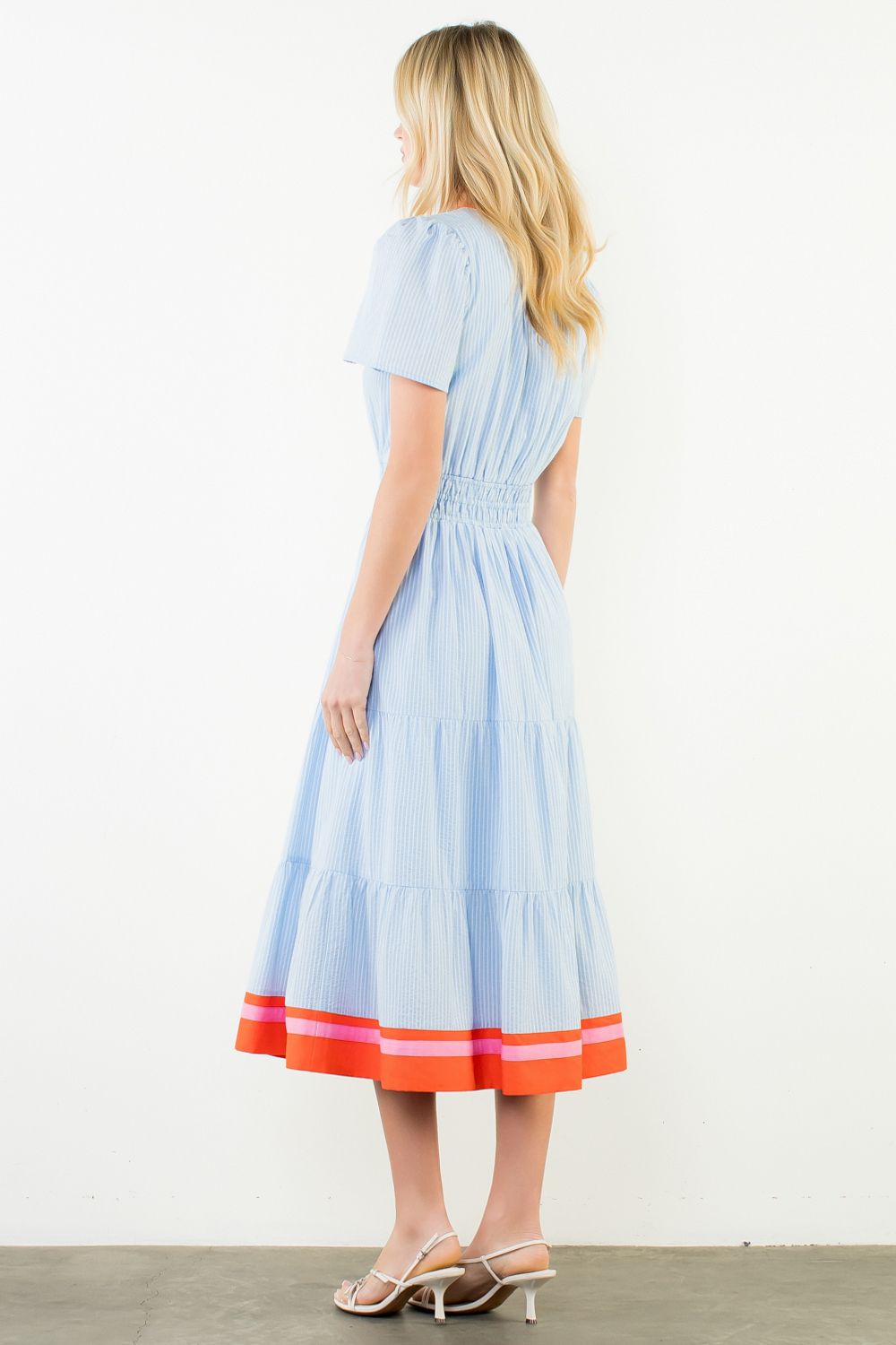 Woman wearing a light blue dress with red trim on a white background