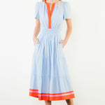 Woman wearing a light blue dress with orange accents on a white background