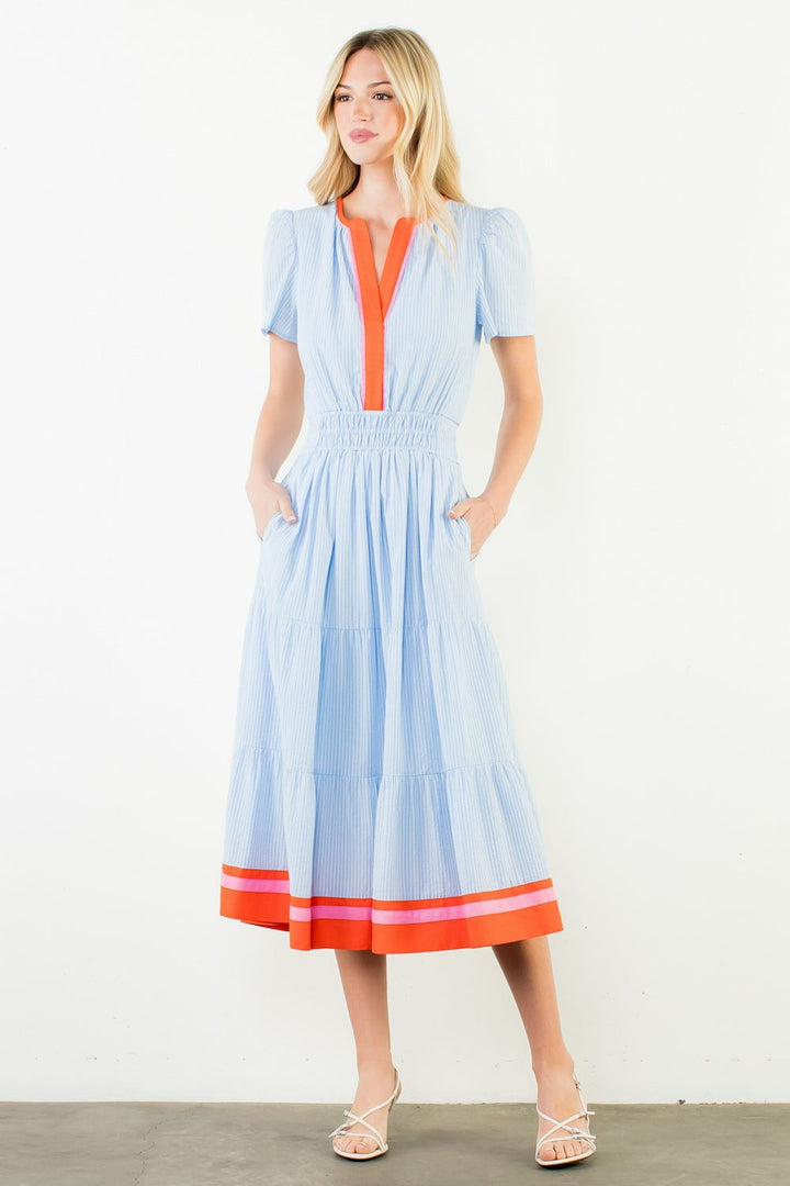 Woman wearing a light blue dress with orange accents on a white background
