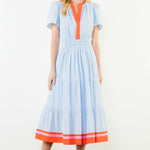 Woman wearing a light blue dress with orange accents on a white background