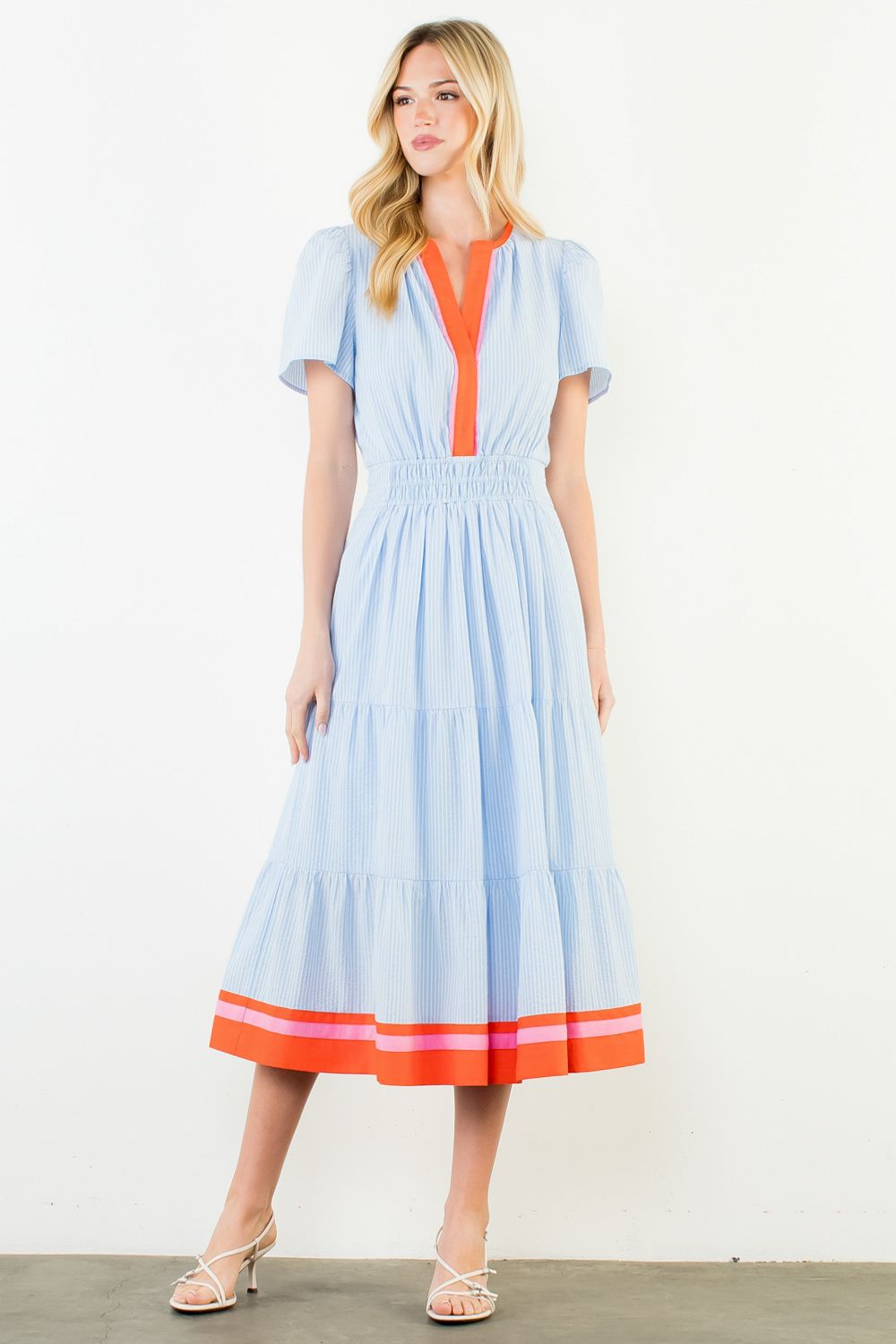 Woman wearing a light blue dress with orange accents on a white background