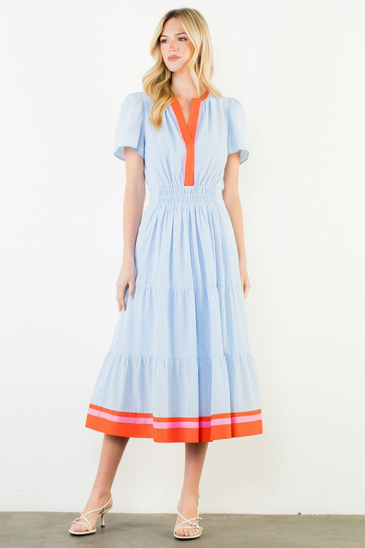 Woman wearing a light blue dress with orange accents on a white background