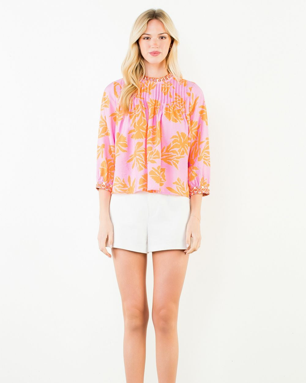 Woman wearing a colorful blouse and white shorts on a white background