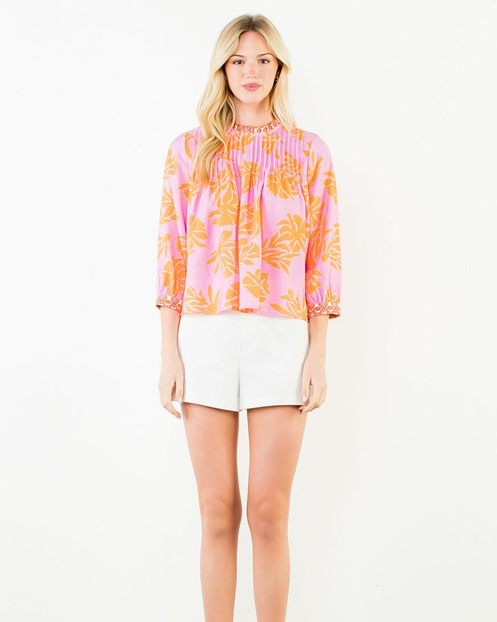Woman wearing a colorful blouse and white shorts on a white background