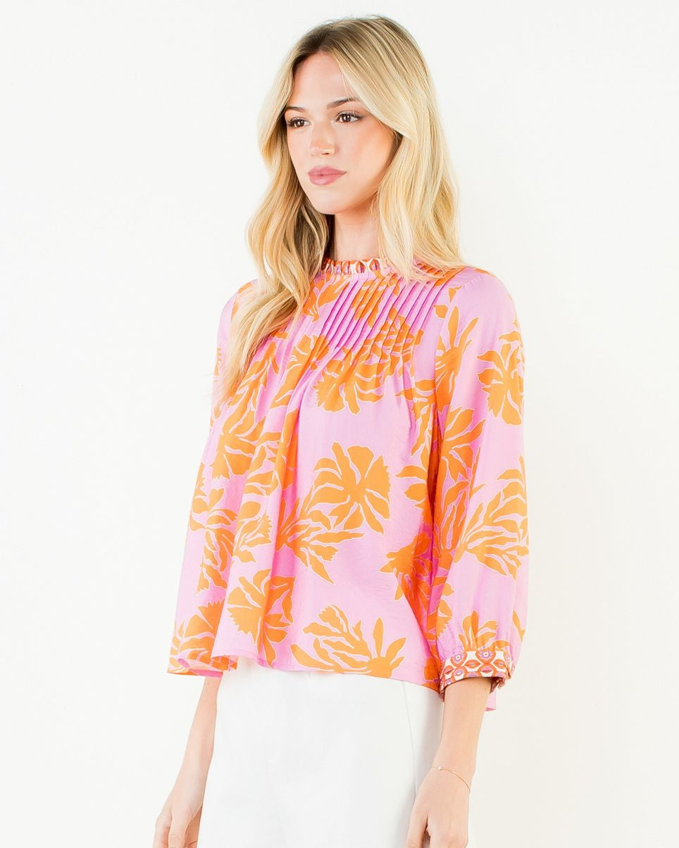 Woman wearing a pink blouse with orange floral patterns on a white background