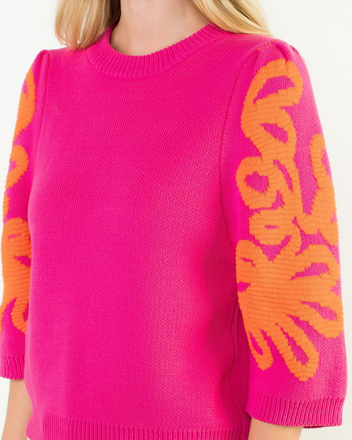 Pink sweater with orange floral patterns on sleeves