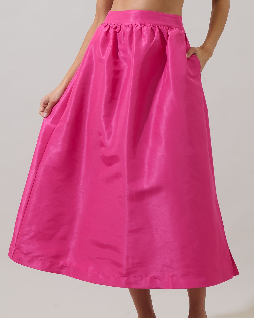 Person wearing a bright pink skirt on a plain background