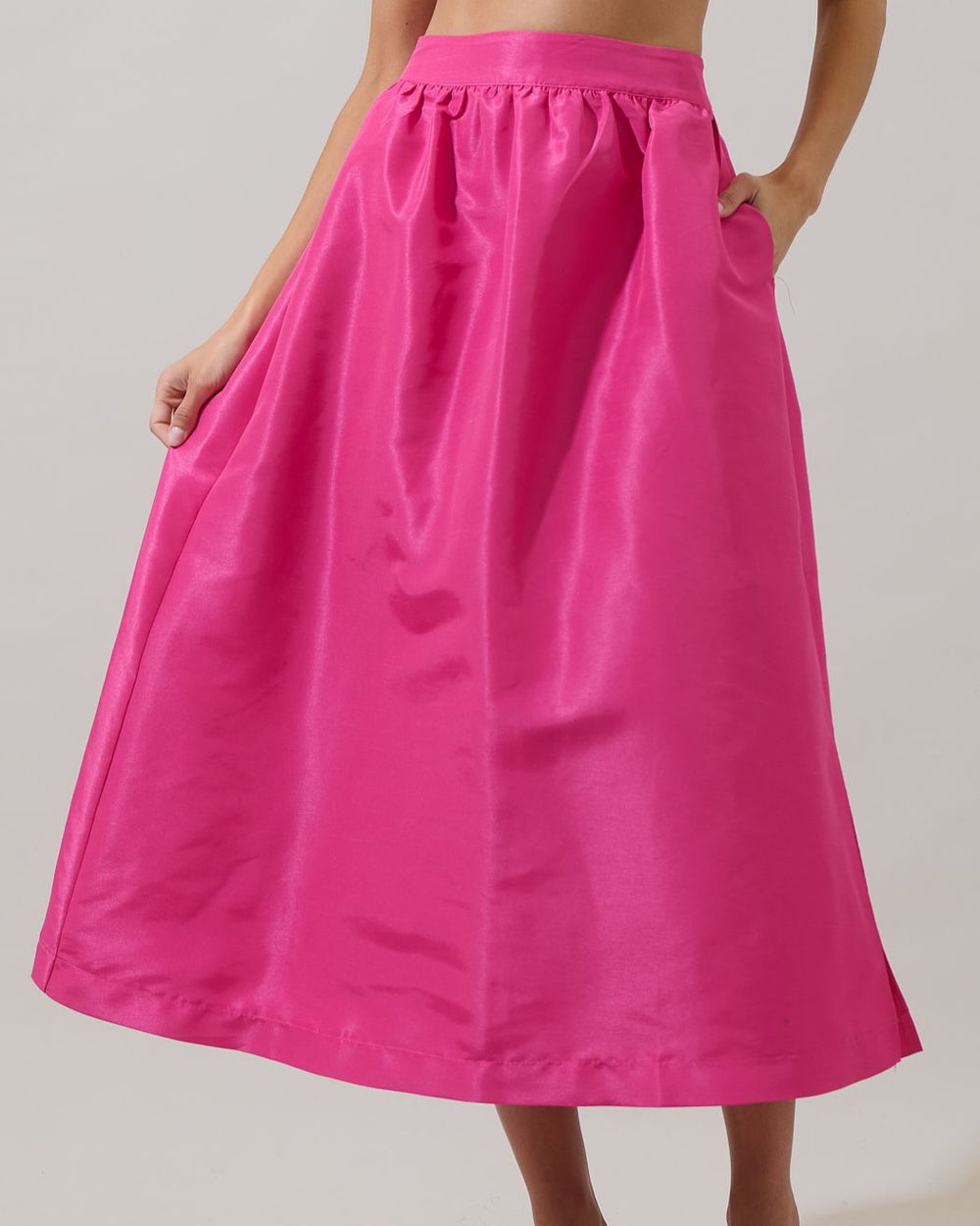 Person wearing a bright pink skirt on a plain background