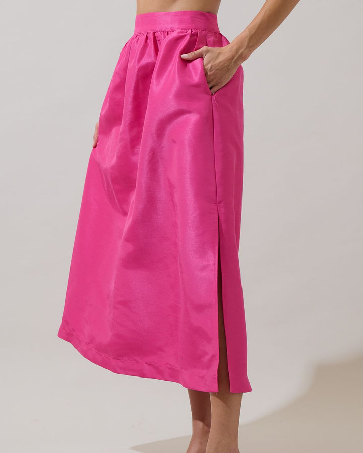 Person wearing a bright pink skirt with a plain background