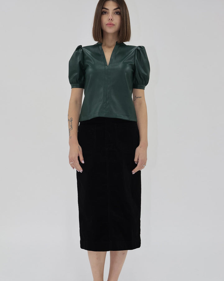 Woman wearing a green blouse with puffed sleeves and a black skirt on a white background