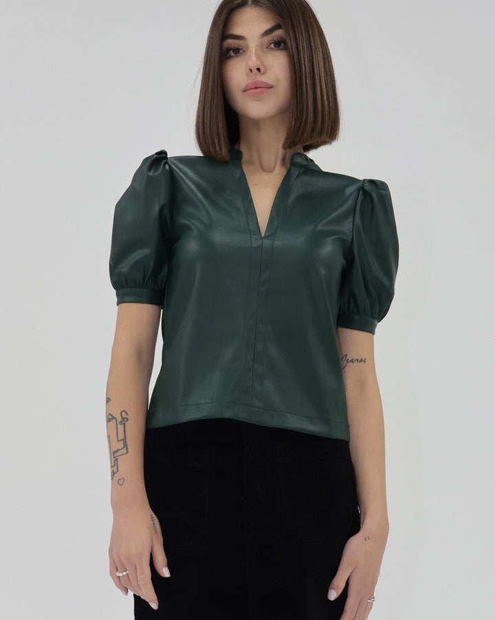 Woman wearing a green satin blouse with puffed sleeves on a plain background