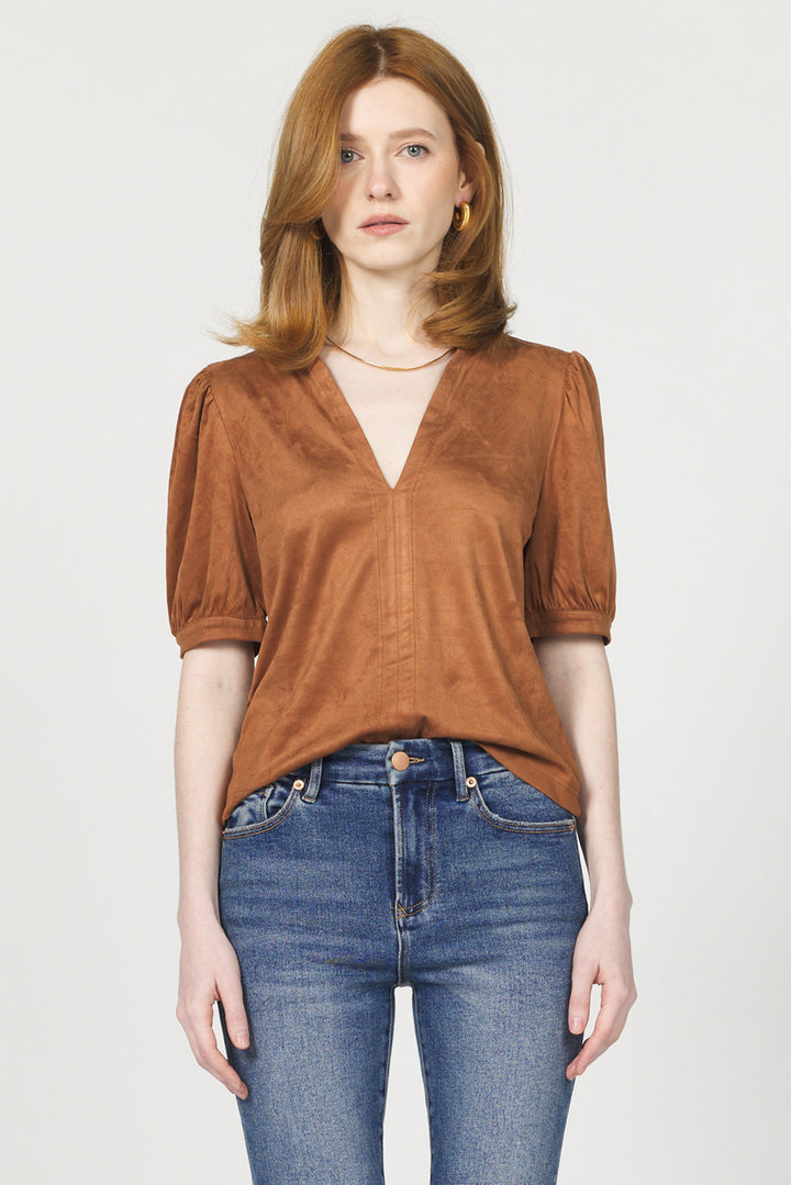 Woman wearing a brown top and blue jeans on a white background