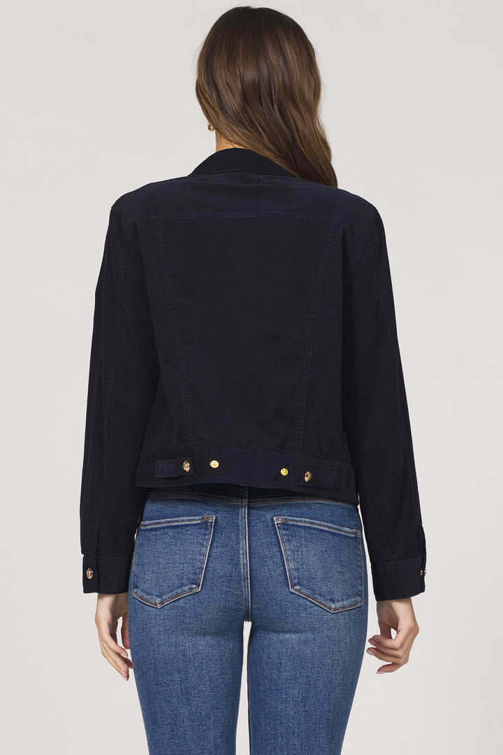 Person wearing a navy jacket and blue jeans on a plain background