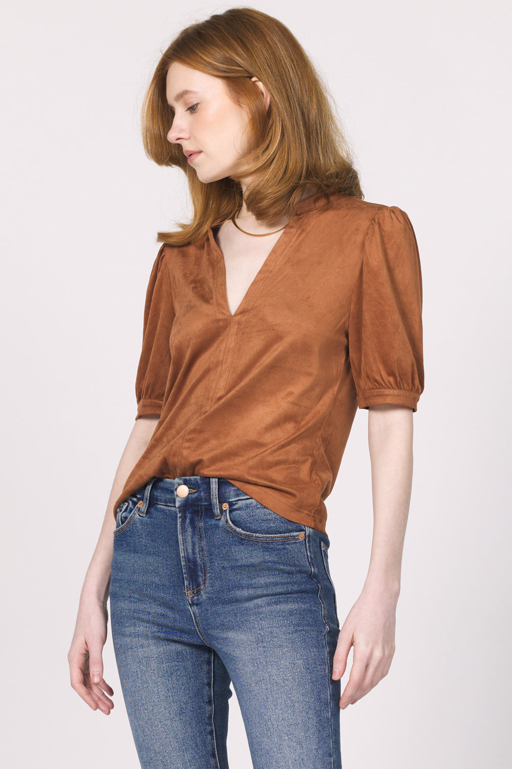 Woman wearing a brown blouse and blue jeans on a white background