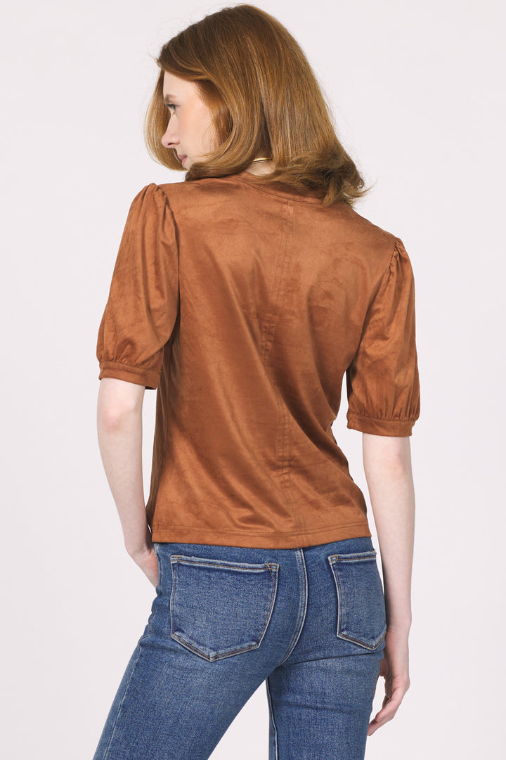 Woman wearing a brown suede jacket and blue jeans on a white background