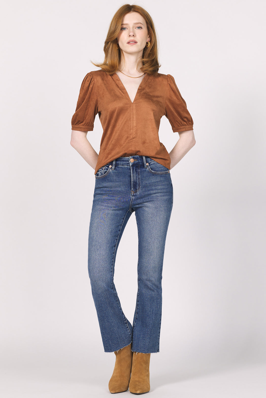 Woman wearing a brown blouse and blue jeans on a white background