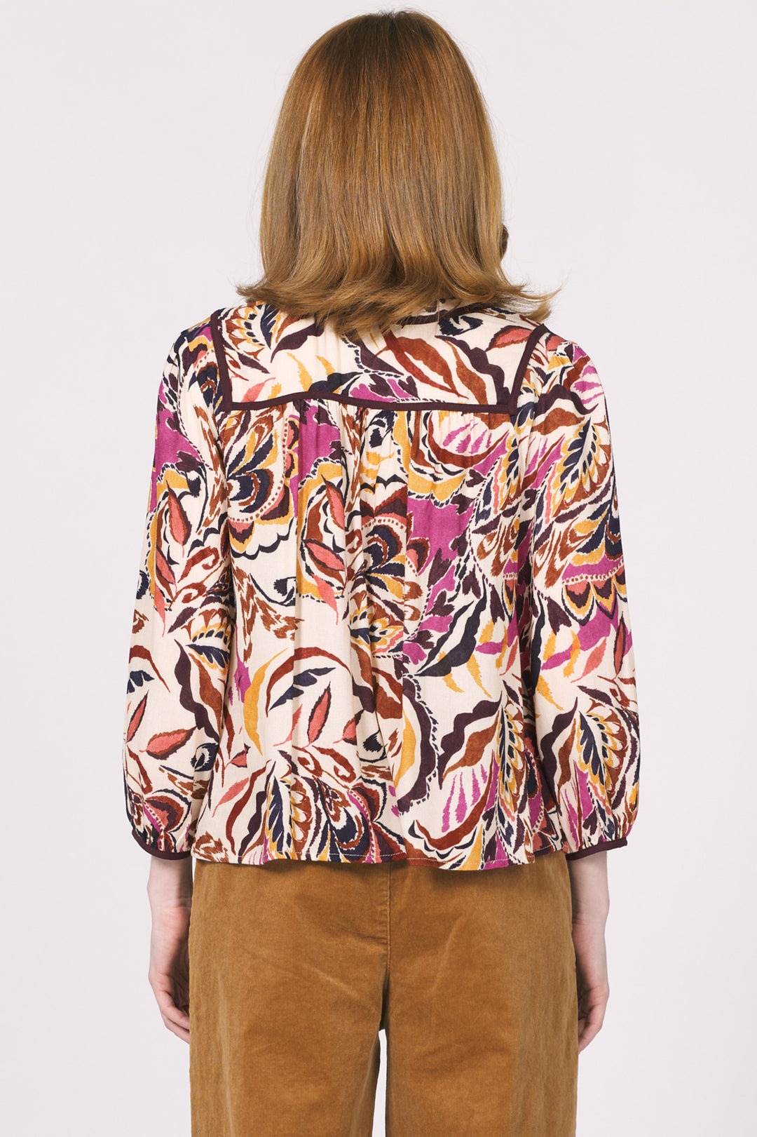 Person wearing a colorful patterned jacket on a plain background