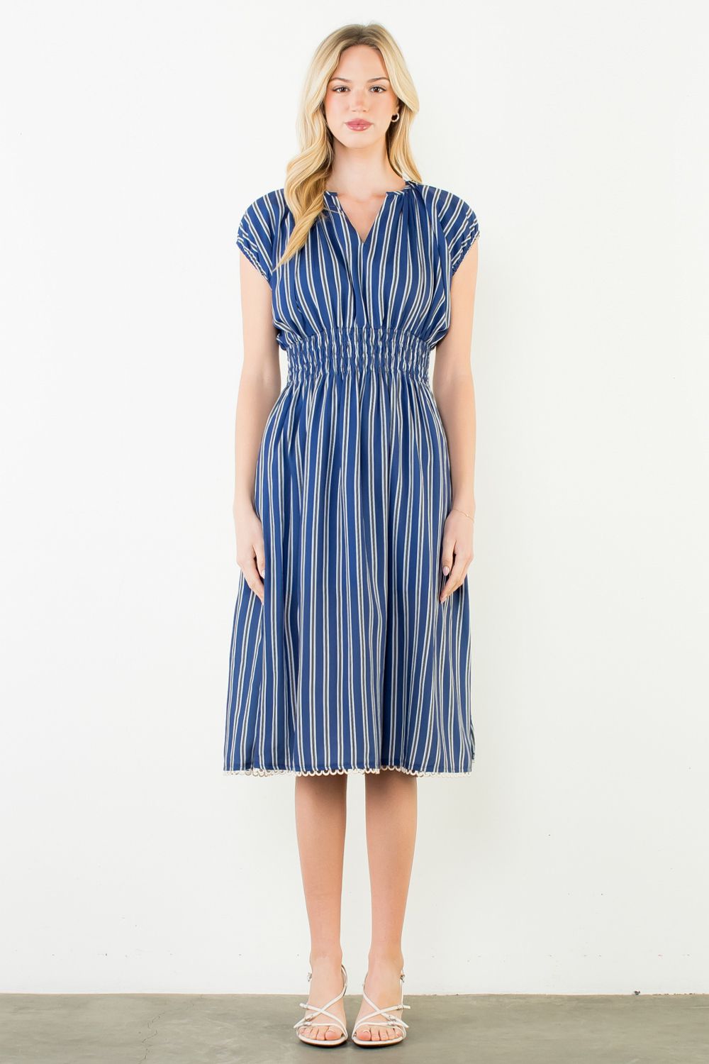 Woman wearing a blue and white striped dress against a white background