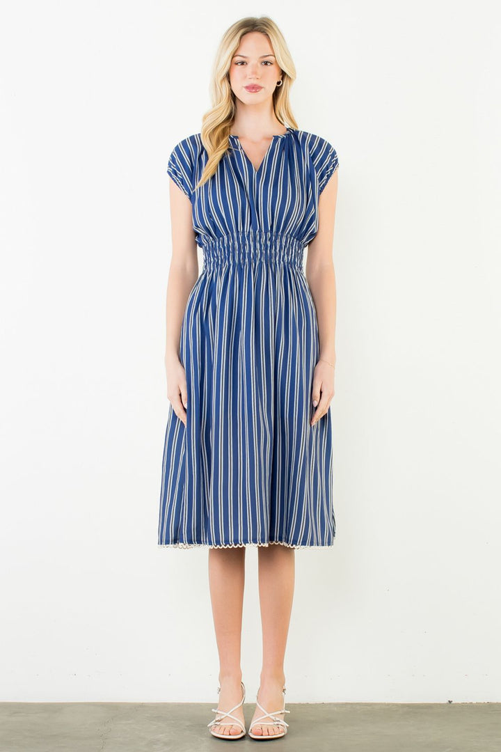 Woman wearing a blue and white striped dress against a white background
