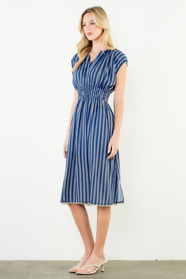 Woman wearing a blue and white striped dress against a white background