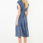 Woman wearing a blue and white striped dress on a plain background