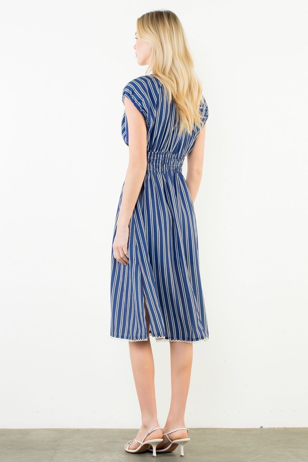 Woman wearing a blue and white striped dress on a plain background