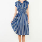 Woman wearing a blue and white striped dress against a white background