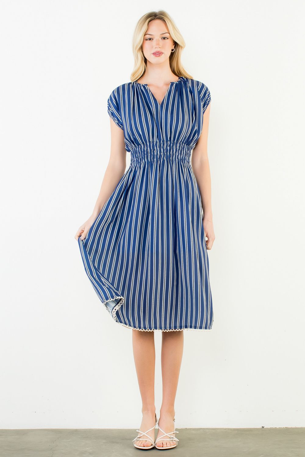 Woman wearing a blue and white striped dress against a white background