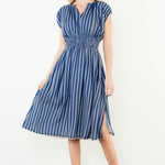 Woman wearing a blue and white striped dress against a white background
