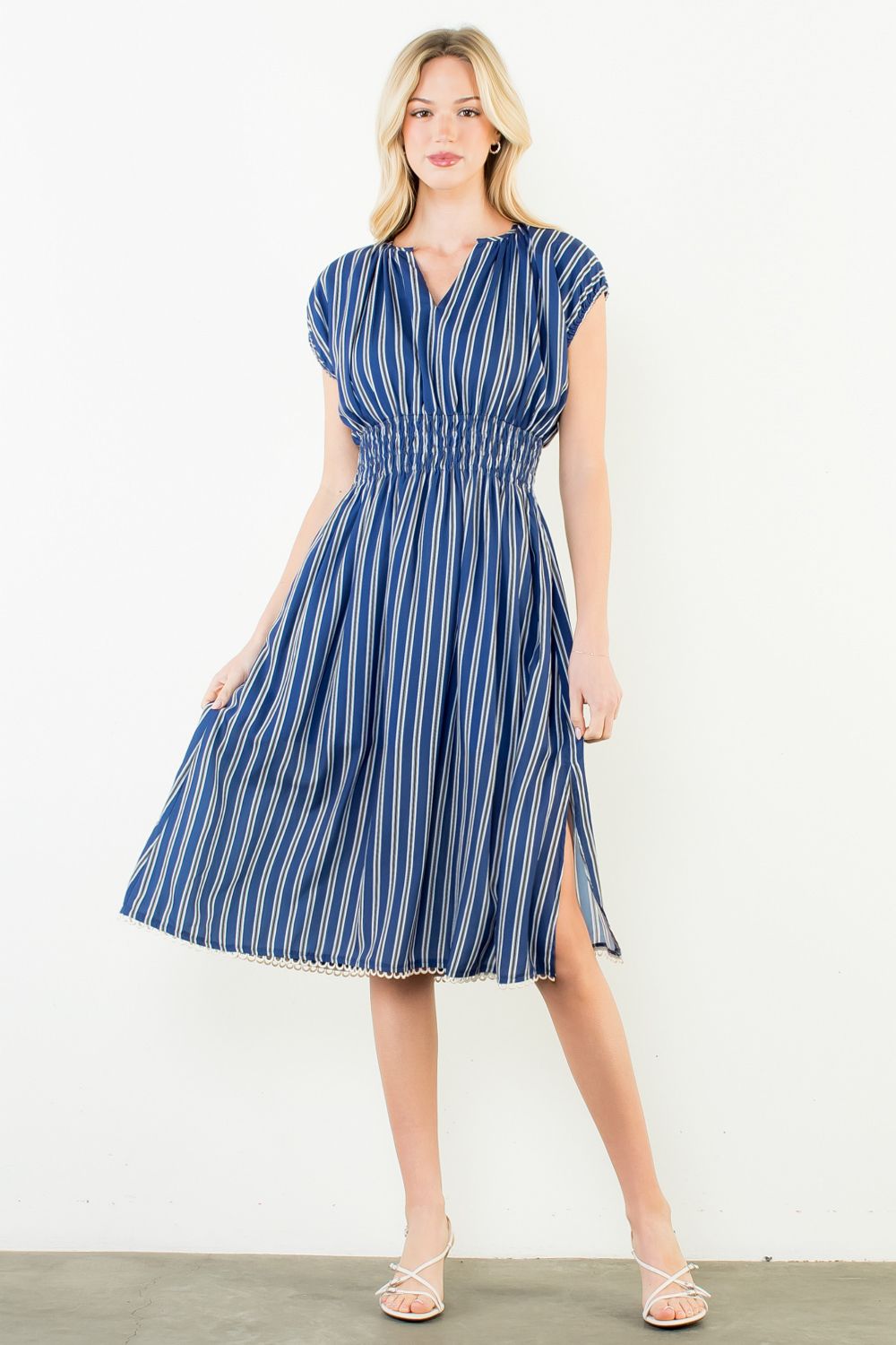 Woman wearing a blue and white striped dress against a white background