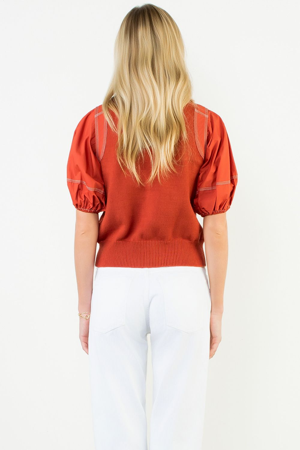 Person wearing a red sweater with puff sleeves on a white background