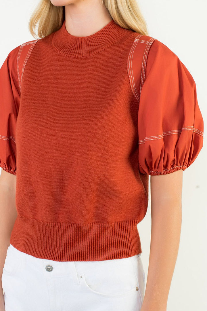 Red sweater with puff sleeves worn by a person on a white background