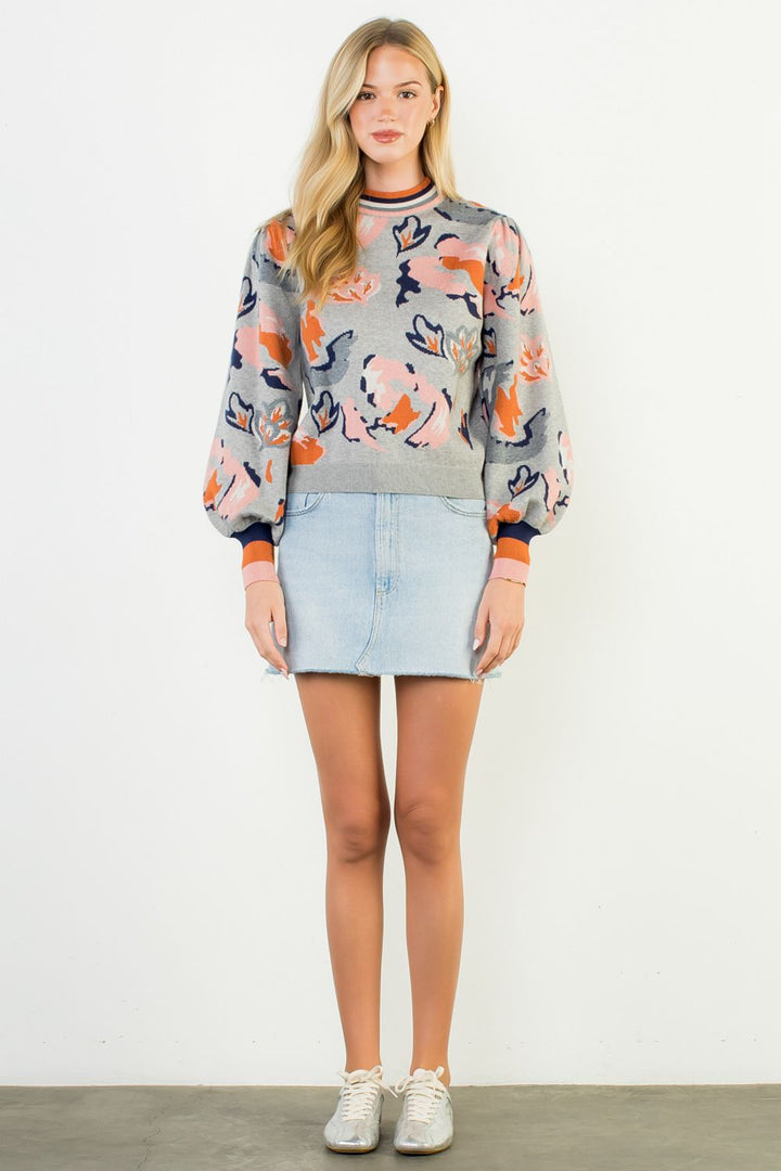 Woman wearing a patterned sweater and denim skirt on a white background