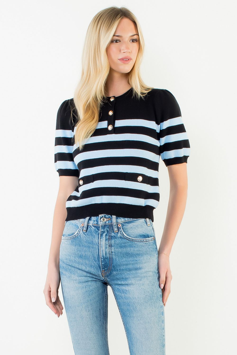 Woman wearing a black and white striped sweater with blue jeans on a white background