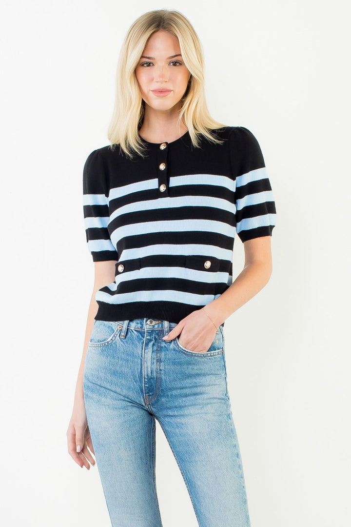 Woman wearing a black and white striped sweater with blue jeans on a white background