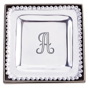 The possibilities are endless! This perfectly giftable trinket tray has multiple uses. Style it as a true bedside or vanity trinket tray, place it in your entryway as your catchall, or use it to entertain as a cocktail napkin holder. This high-polished cast aluminum trinket dish features dimensional beaded edge and engraved center initial. Perfectly giftable in elegant paper wrapped gift box.  Dimensions: 7" x 7"